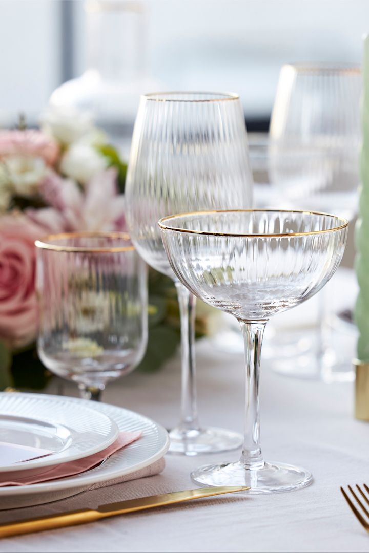 Glasen från kollektionen Palermo från Lyngby Glas har en elegant gyllene kant och visas här på ett stilfullt dukat bord i vitt, rosa och guld.
