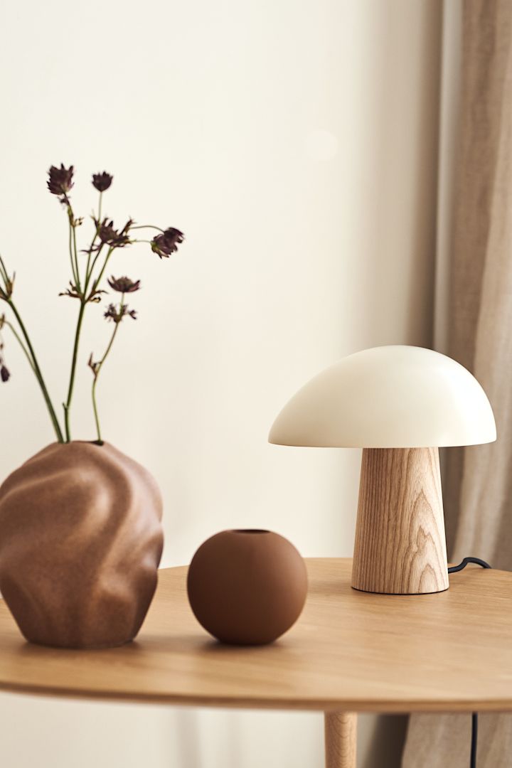 Inred ditt vardagsrum med beige inredning tillsammans med olika nyanser av beigt för en härlig kontrast i ditt hem. Här ser du Drift vas och Ball vas från Cooee Design i murriga toner tillsammans med Night Owl bordslampa från Fritz Hansen i vita samt beigea toner.