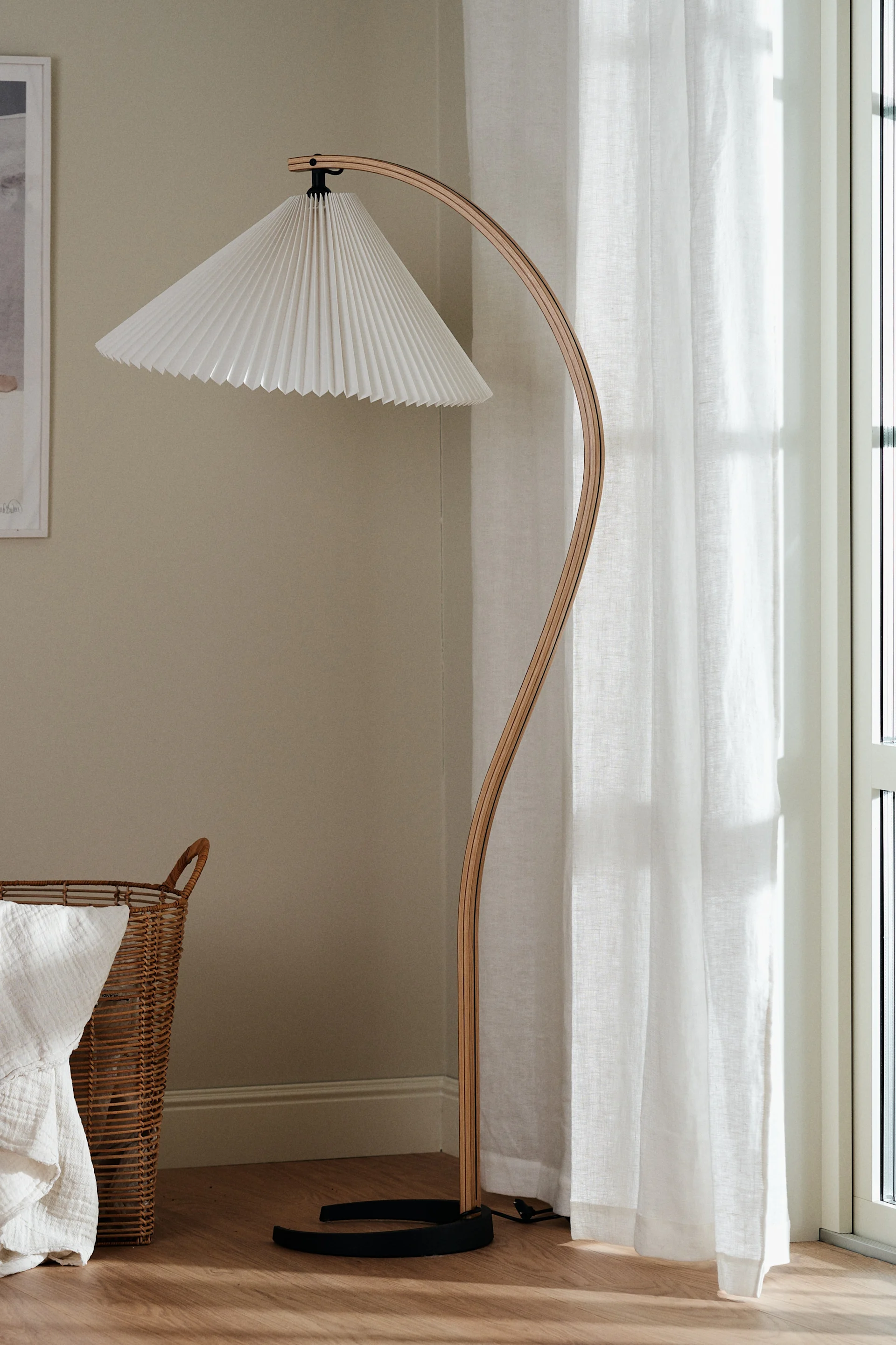 Skapa ett feng shui-vardagsrum genom att inreda med tunna gardiner för att släppa in naturligt dagsljus. Här ser du Gubi golvlampa och Scandi Living gardiner.