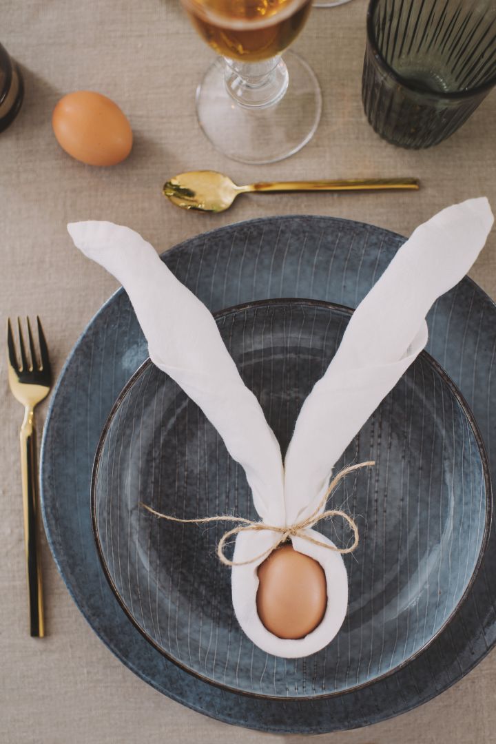 En linneservett från Broste Copenhagen kan med en enkel servettvikning bli ett par kaninöron, en fin påskdekoration uppskattad av varje gäst.