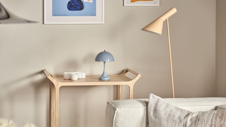 Panthella portabel bordslampa tillsammans med AJ golvlampa är en fin kombination, här i ljusblått och beige i vardagsrumsmiljö med beige soffa och rullvagn i trä.