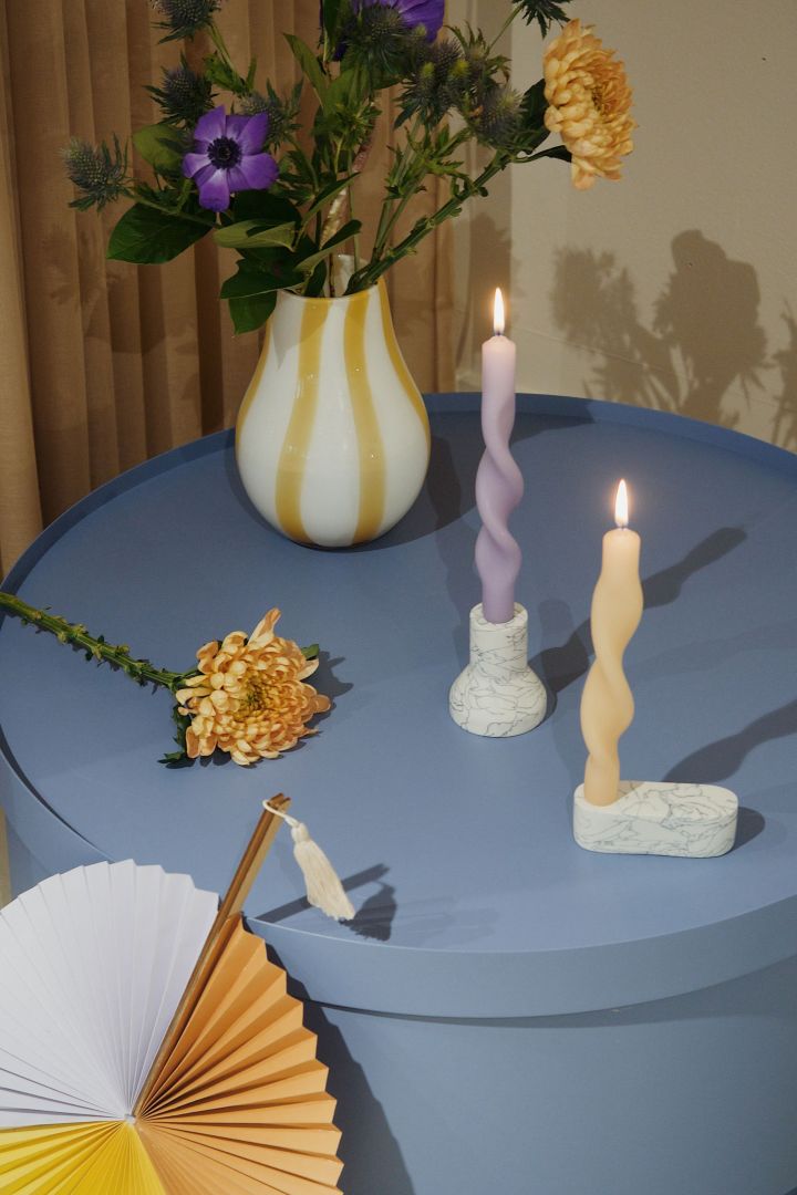 Twistade ljus i lavendelila och citrongult på ett himmelsblått bord - Broste Copenhagen visar upp färgtrender 2022.