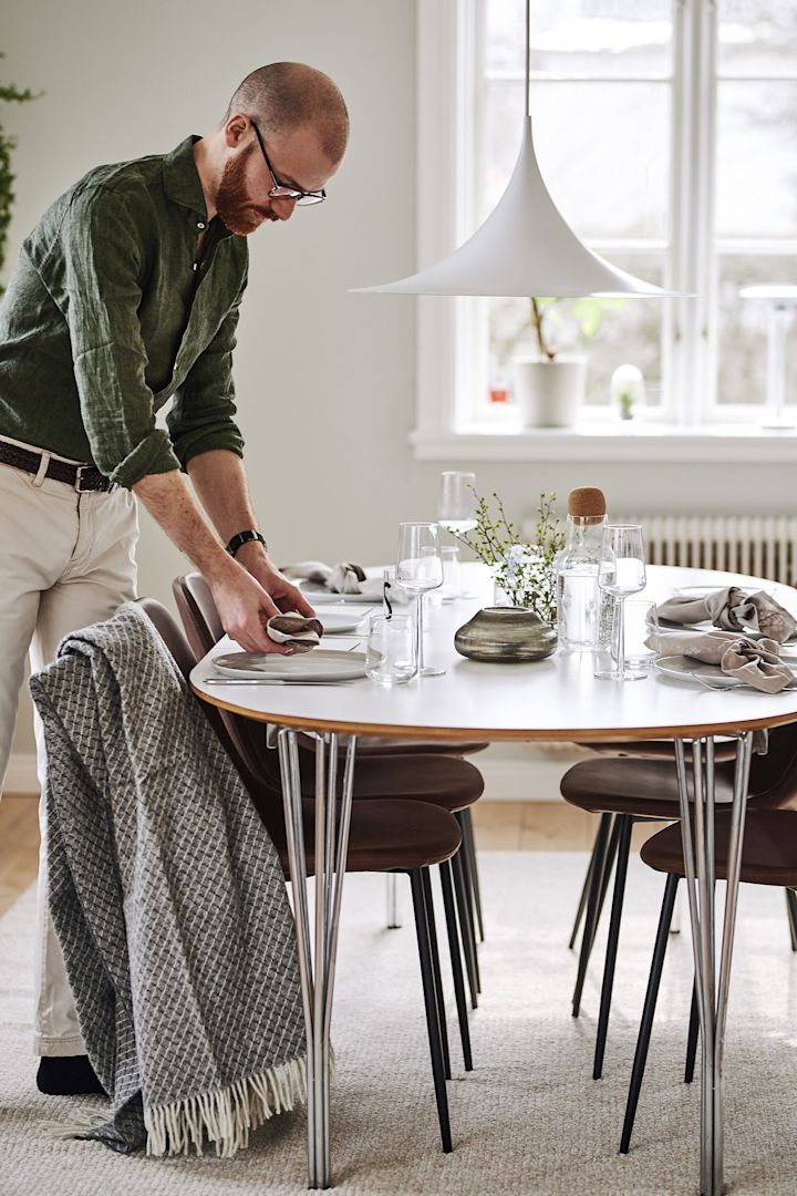 En ljus matplats inredd i klassisk skandinavisk stil med inredning som Semi lampa från Gubi och Forms stolar i läder från House Doctor. 