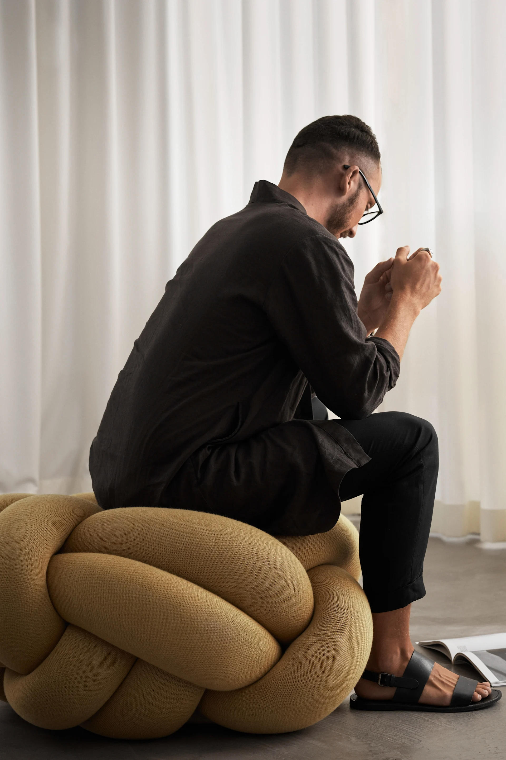 Man sitter på XL Knot-kudden i gult.