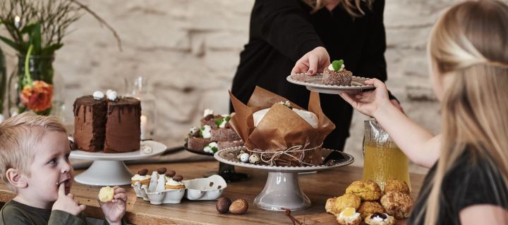 Ett dessertbord står uppdukat och det bjuds på påskdessert med råge: morotstårta, muffins och rulltårta serveras till gästerna. 