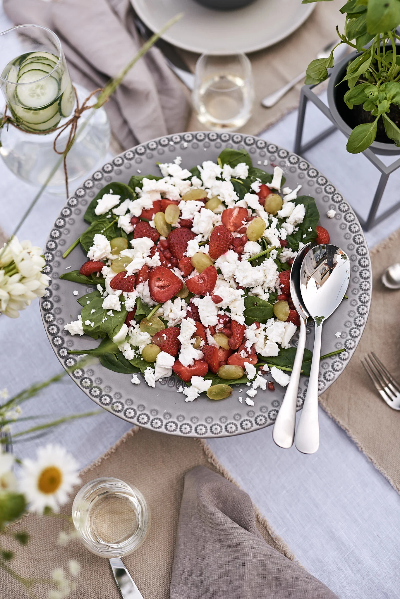 En härlig sommarsallad på jordgubbar och fetaost serverad på ett grått tårtfat står som huvudrätt på sommarlunchen.