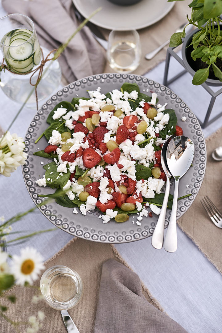 En härlig sommarsallad på jordgubbar och fetaost serverad på ett grått tårtfat står som huvudrätt på sommarlunchen. 