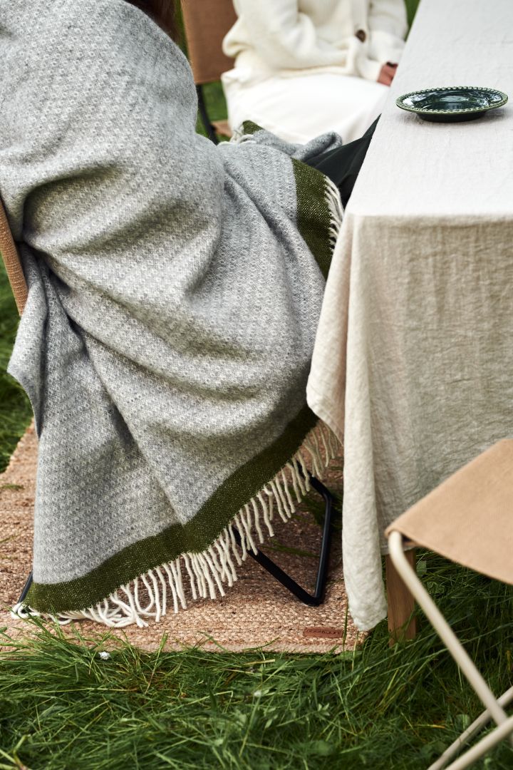 En sommardukning i trädgården blir inte komplett utan mjuka textilier såsom denna härliga Hampus ullpläd från Klippan Yllefabrik i gröna och grå toner.