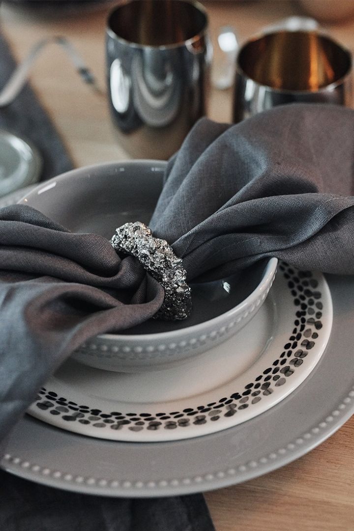 Tallrikskuvert i gråa toner med romantiska tallrikar från Scandi Living, mörkgrå linneservett och silverfärgad servettring utgör denna nyårsdukning i silver. 