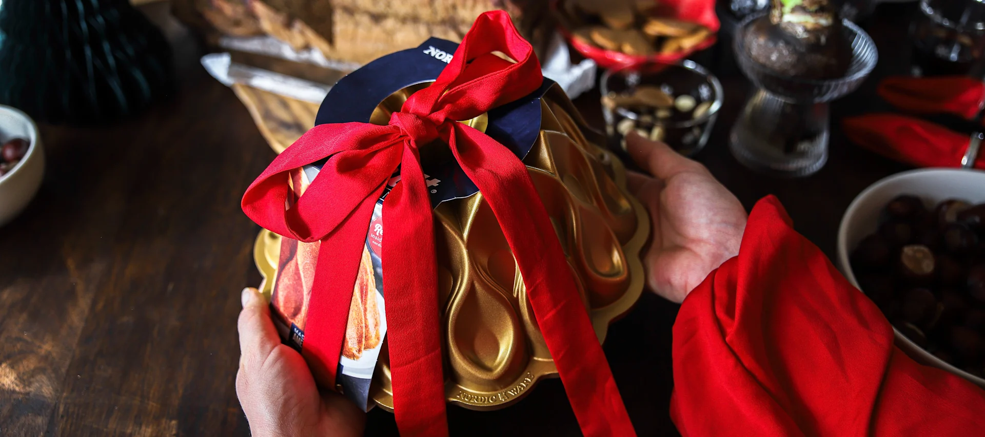 En bakform från Nordic Ware med ett rött knutet band runt som ett tips på julklapp.