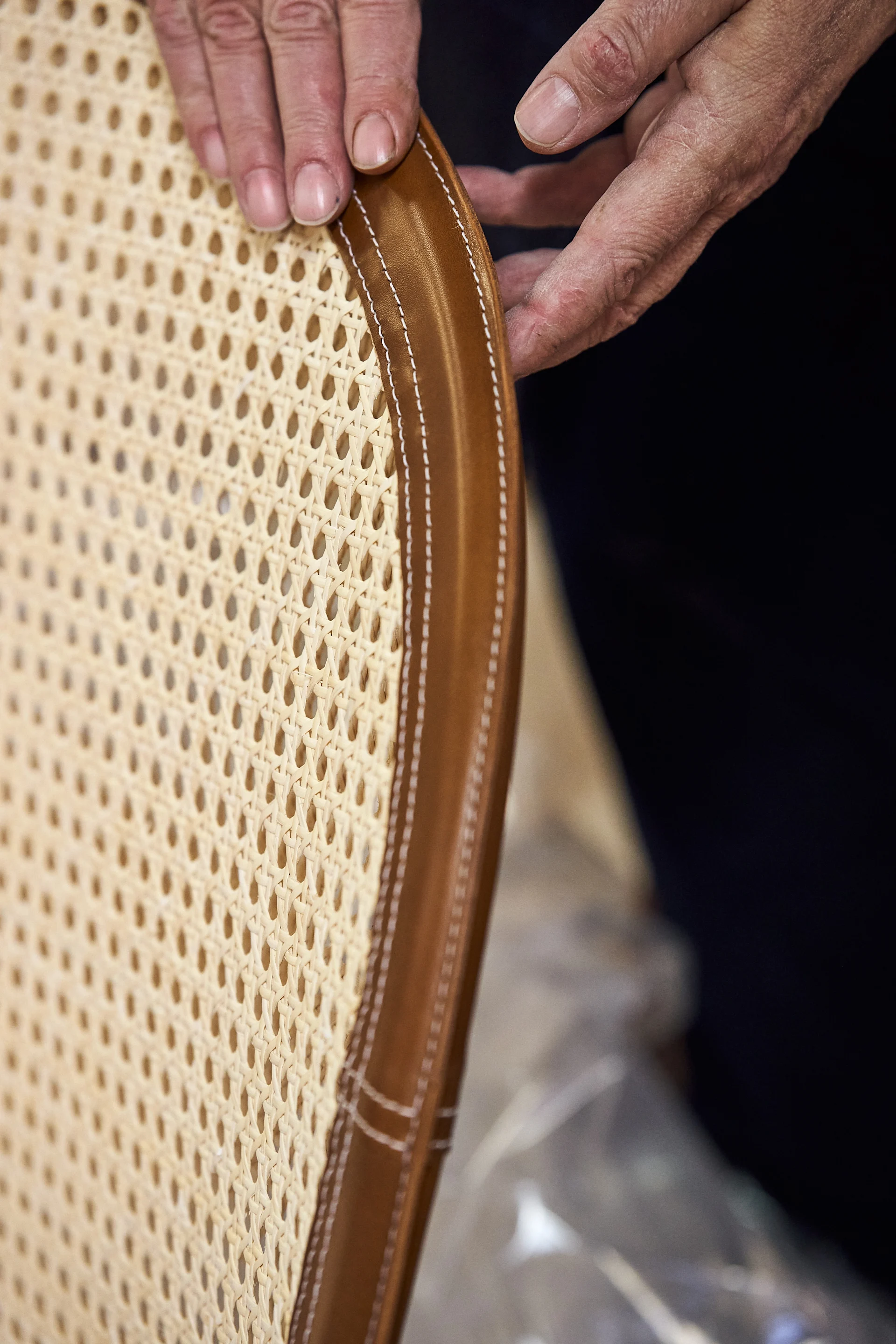 Detaljbild på Dandy fåtölj från Gärsnäs där rotting möter cognacsfärgat läder.