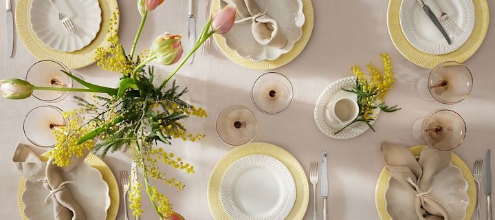 En färgglad bordsdekoration till påsk, bestående av Stripes-tallrikar från Mateus, glas från Byon och servetter från Scandi Living.