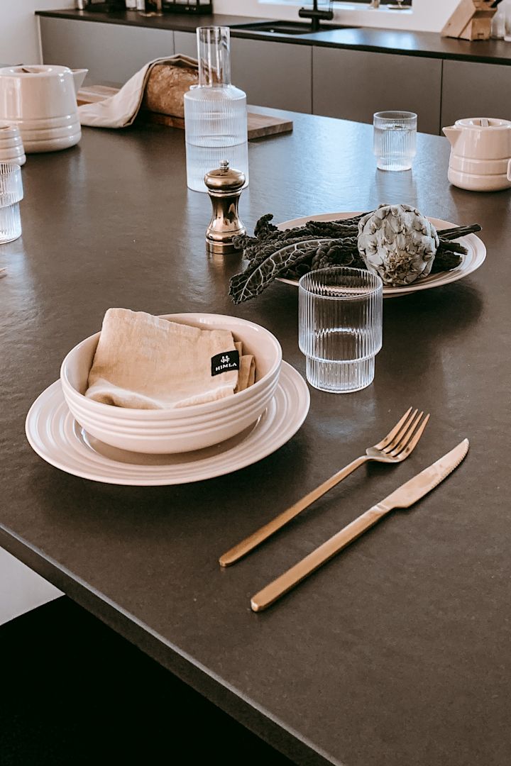 Anela Tahirovic @arkihem har inrett köksön med Lines porslin från NJRD i beigt tillsammans med Ripple glas och karaff från Ferm Living.