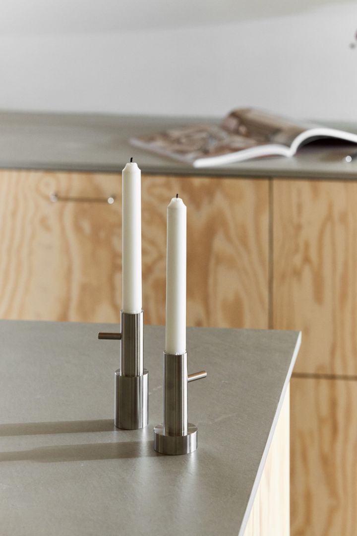 Ljusstakar i rostfritt stål med design av Jaime Hayon för Fritz Hansen står på en köksö. 