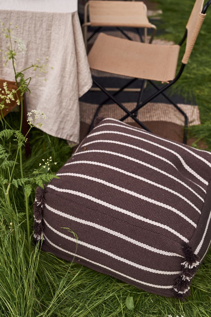 En sommardukning i trädgården blir inte komplett utan mjuka textilier kring bordet såsom denna härliga Lina sittpuff från OYOY i brunt.