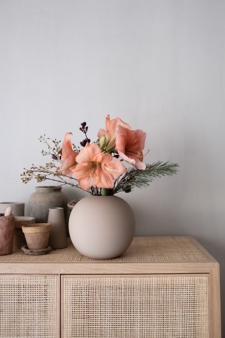Stilleben på inredning med rund vas från Cooee Design och aprikosfärgade blommor på en byrå. 
