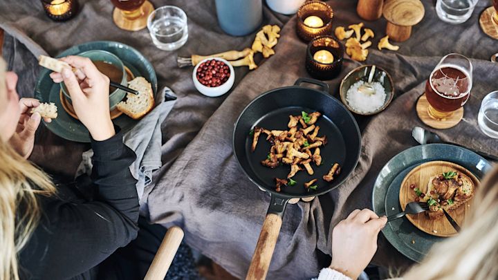 En rustik dukning med Fiskars stekpanna i gjutjärn från serien Norden där kantareller har stekts och serveras direkt ur stekpannan. 