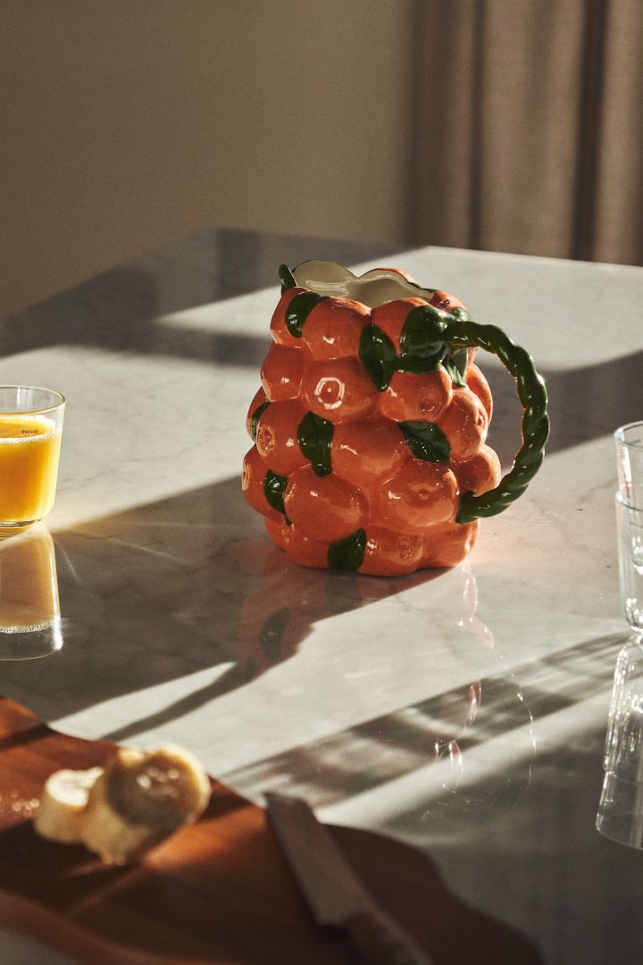 Kanna i bullig form i orange och grönt med mandariner som inspiration på ett frukostbord. 