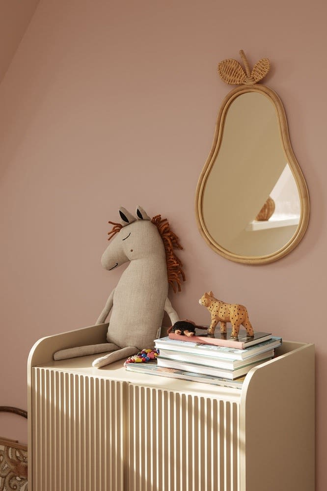 Kudden Safari Horse från Ferm Living ligger på en byrå i ett barnrum med spegeln Pear hängande bredvid.