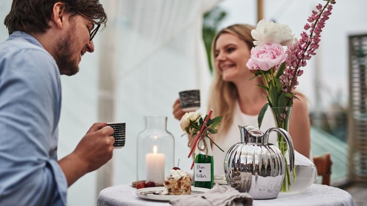 Duka romantiskt till alla hjärtans dag med bakelse, kaffe och blommor på bordet. 