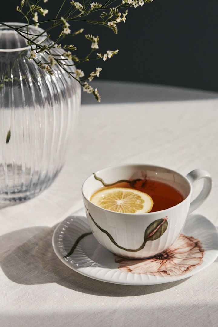 Hammershøi Poppy tekopp med fat fylld med citronte bredvid Hammershøi vas i klarglas från Kähler.