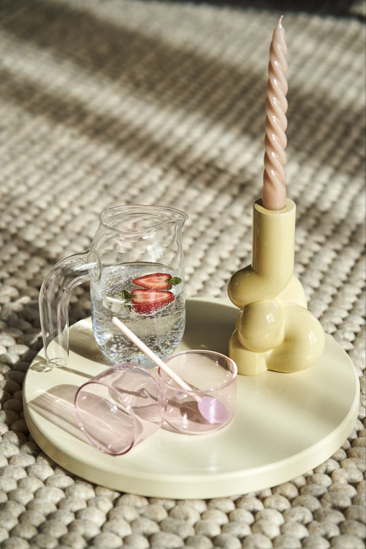 Chopping Board skärbräda i Off-white tillsammans med Jug kanna i klarglas, Tint glas i rosa, rosa Round glassked, W&S Soft ljusstake i Soft Yellow med Candle Twist peach ljus från HAY.