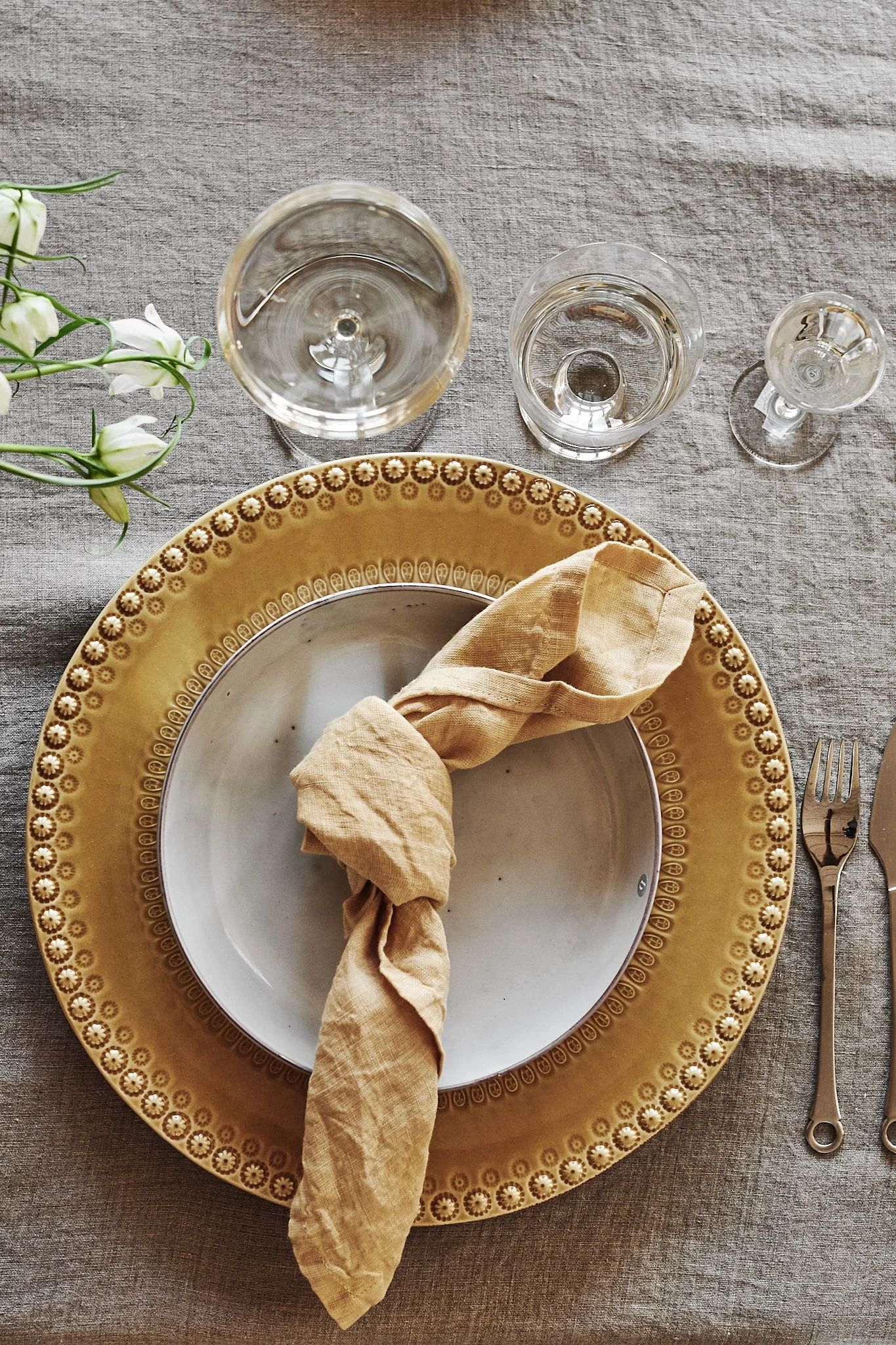 En sommardukning i gult och grått där tallrik från PotteryJo mixats med assietten Nordic Sand från Broste Copenhagen.