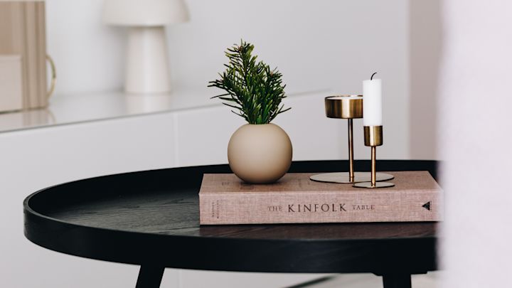 Liten sandfärgad Ball vas från Cooee Design och ljusstakar i mässing står som stilleben på soffbordet.