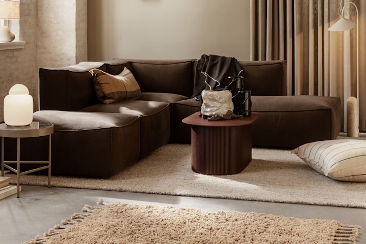 Vardagsrum i höstens färger med mörkrött bord, brun soffa, beige lampa och kudde från Ferm Living - komponenter som speglar höstens inredningstrender 2021.