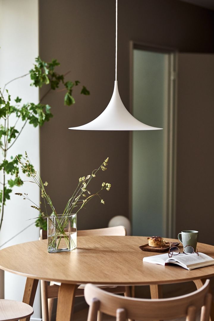 Vit Semi-taklampa från Gubi är en sann designlampa och klassiker - här över matbordet där den ger ifrån sig perfekt stämningsbelysning. 