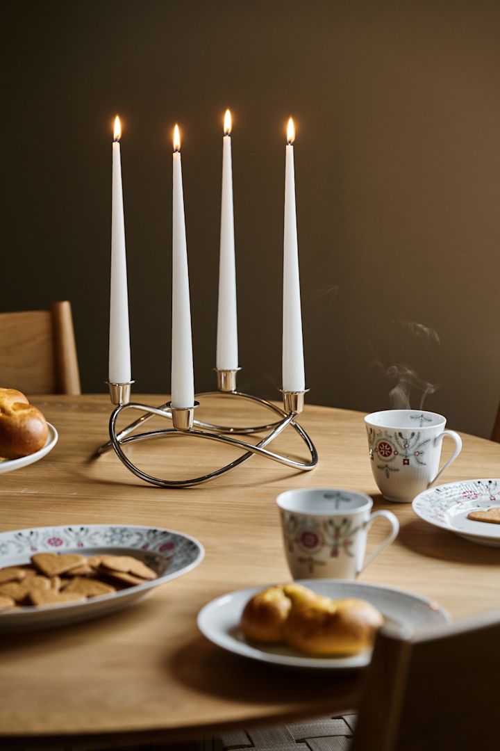 Adventljuset Season står på ett julbord med pepparkakor och saffransbullar. 