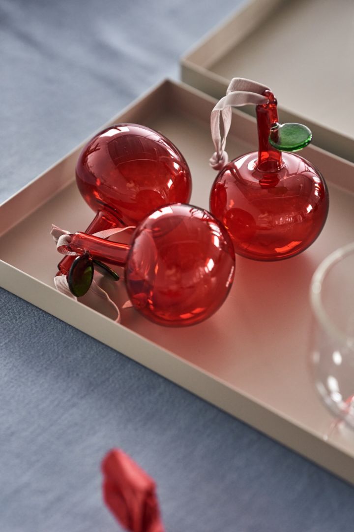 En elegant juldukning i 4 olika stilar enligt Nest Trends; Cultivate, Nurture, Boost och Share. Här är en dukning inom Share-trenden med Iittala glasäpplen i rött på beige bricka från Cooee Design.