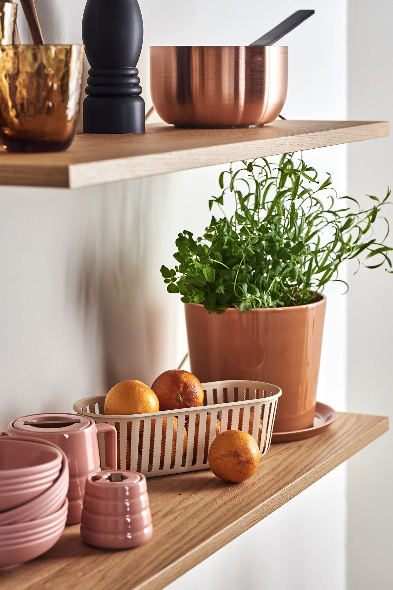 Maze Pythagoras-hylla i ek stylad med rosa porslin, kruka, örter och citrusfrukter.