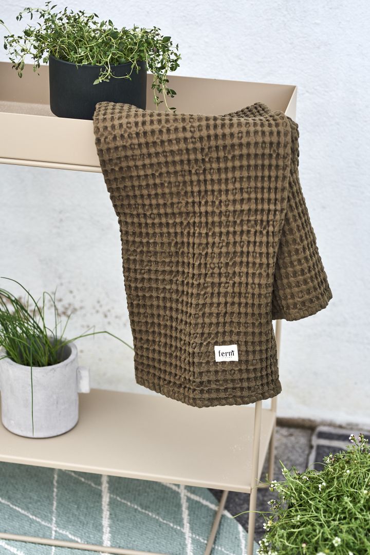 Olivgrön handduk från Ferm Living och ett konsolbord i beige färg fångar det bästa av uteplats trender.