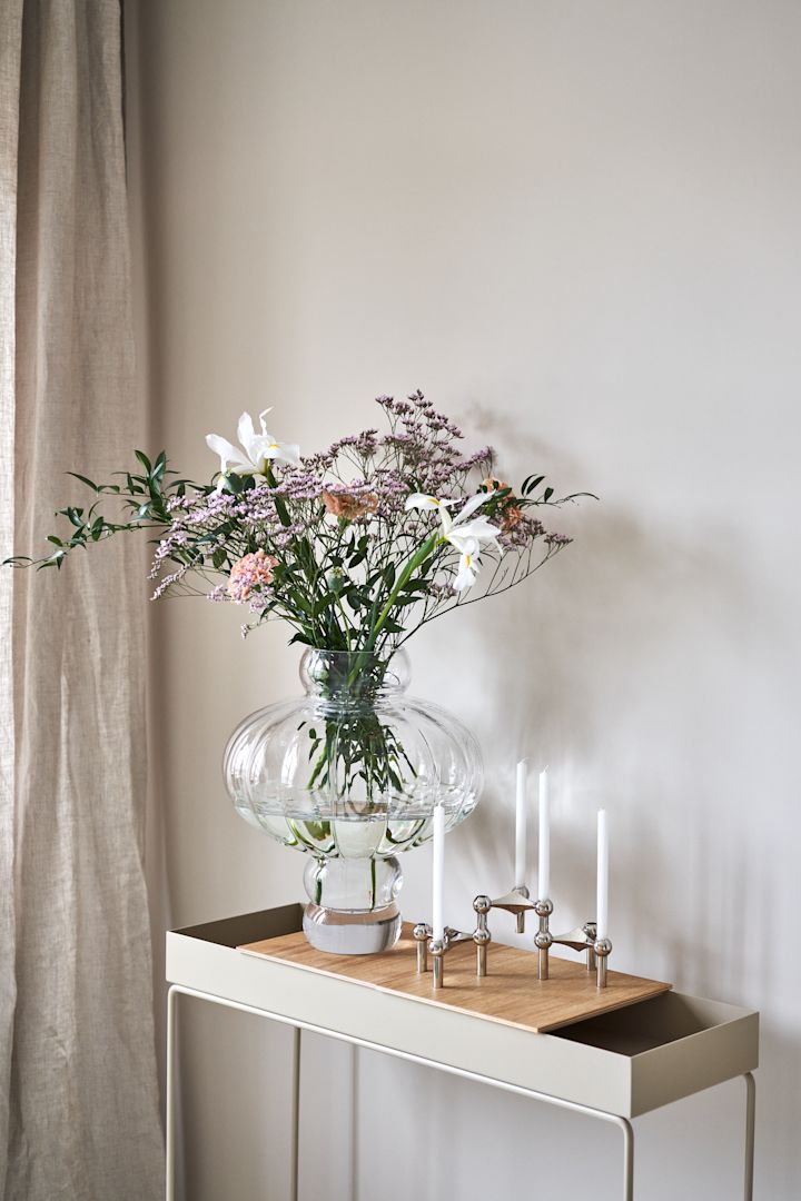 Runda och eleganta Balloon vas i klarglas från Louise Roe Copenhagen som står bredvid Stoff nagel ljusstake på Plant Box från Ferm Living är en av säsongens stora vaser för vårens blomster.