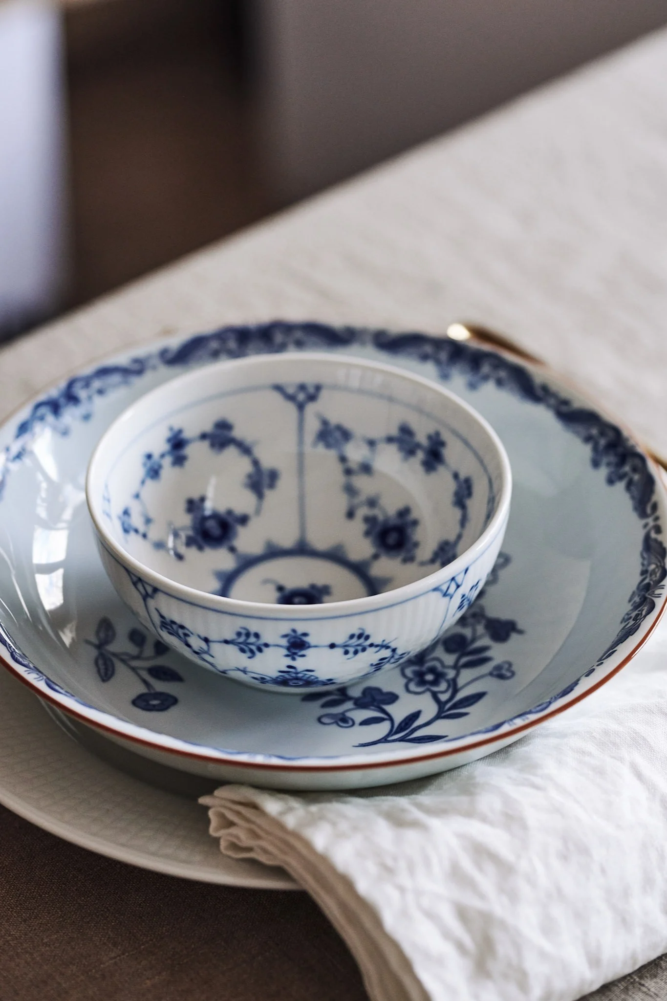 En blåvit sommardukning med blandat porslin som Ostindia djup tallrik och Musselmalet räfflat från Royal Copenhagen.