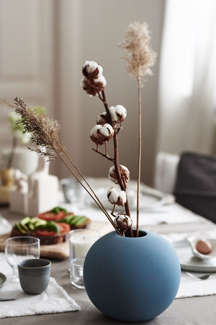 På frukostdukningen står Cooee Design Ball vas blå fylld med torkat vass – helt enligt inredningstrender.