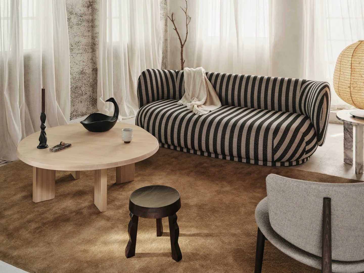 Mysigt vardagsrum med svart-vitrandig soffa, ljust soffbord i trä och rustikt tak med träbjälkar.