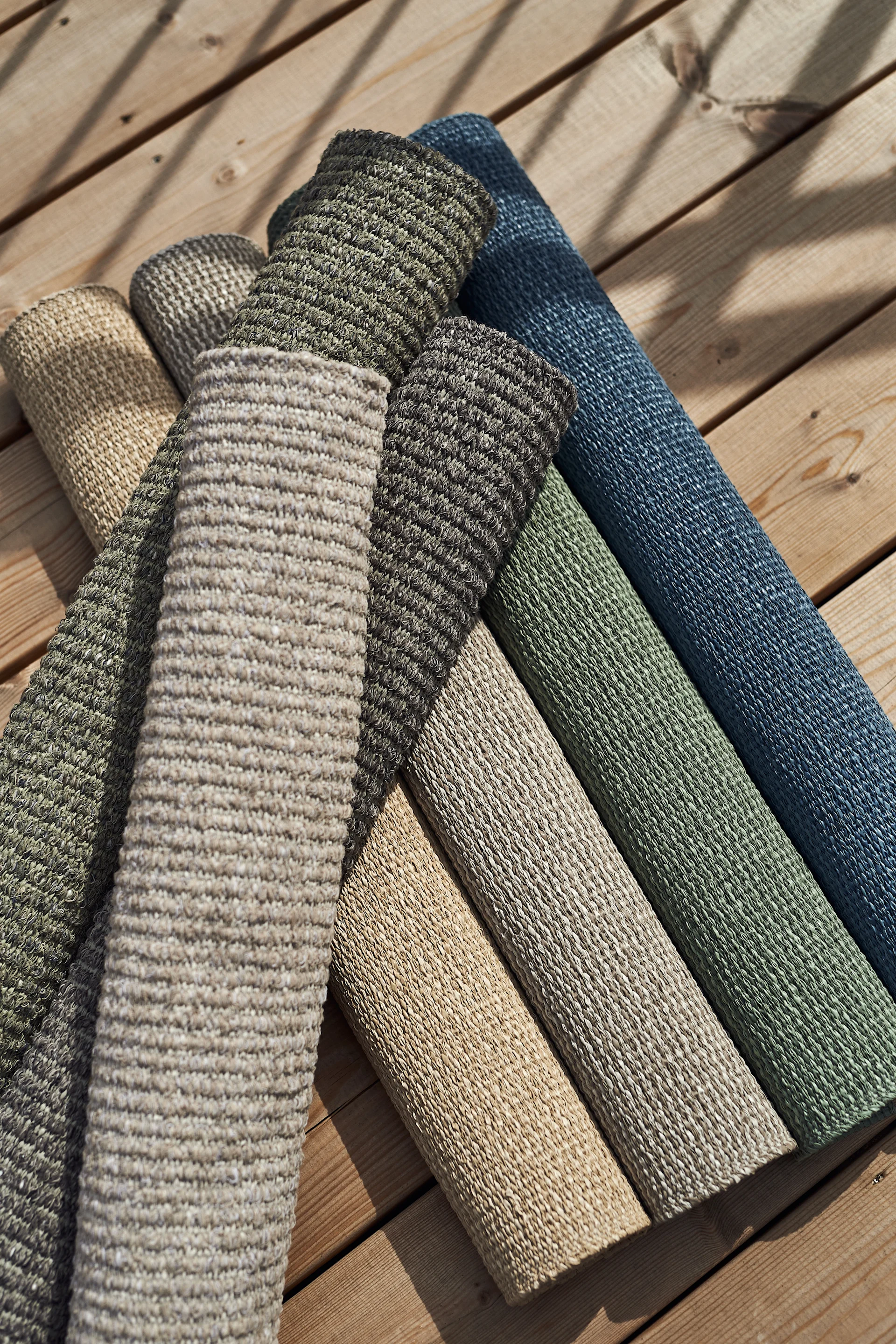 Balkonginspo, rullade plastmattor i olika färger på trädäck. Plastmattor är perfekta balkongmattor då dem tål väder och vind samtidigt som det är enkelt att göra rent vid eventuella fläckar.