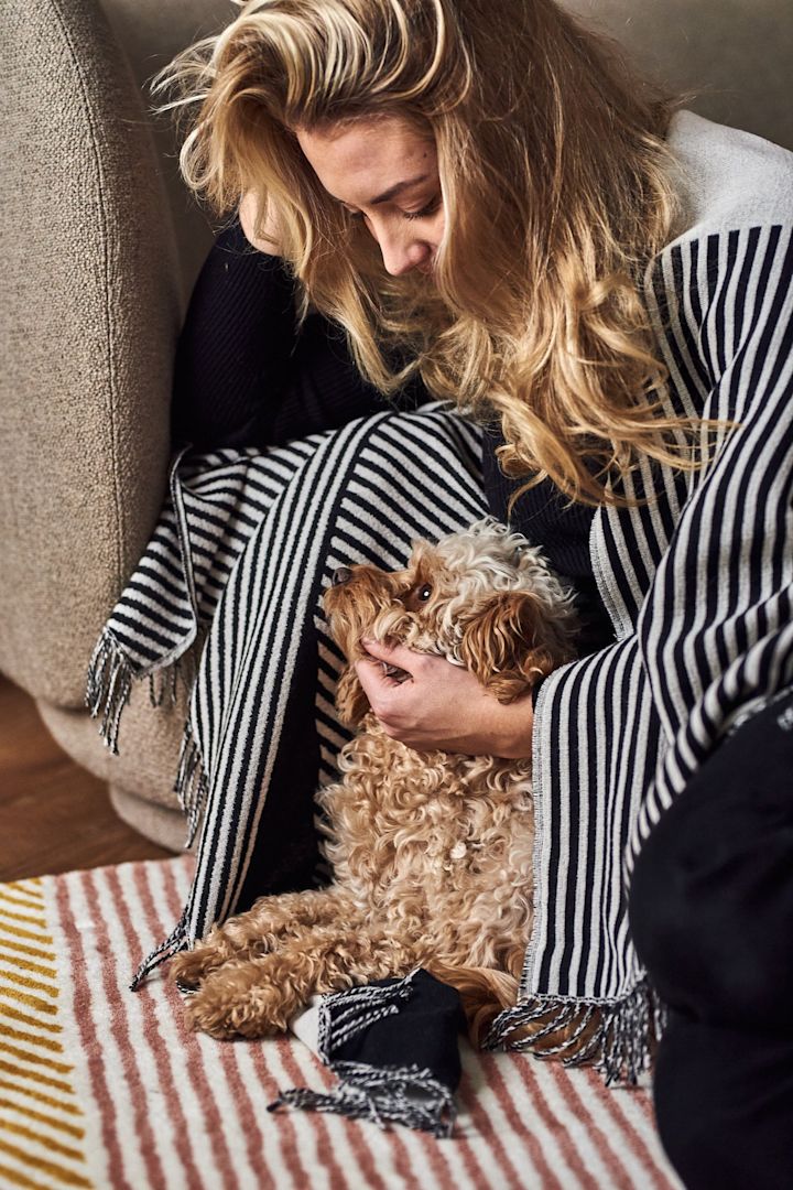 Elin Skoglund och hennes hund Selma myser på en färgglad matta från NJRD.