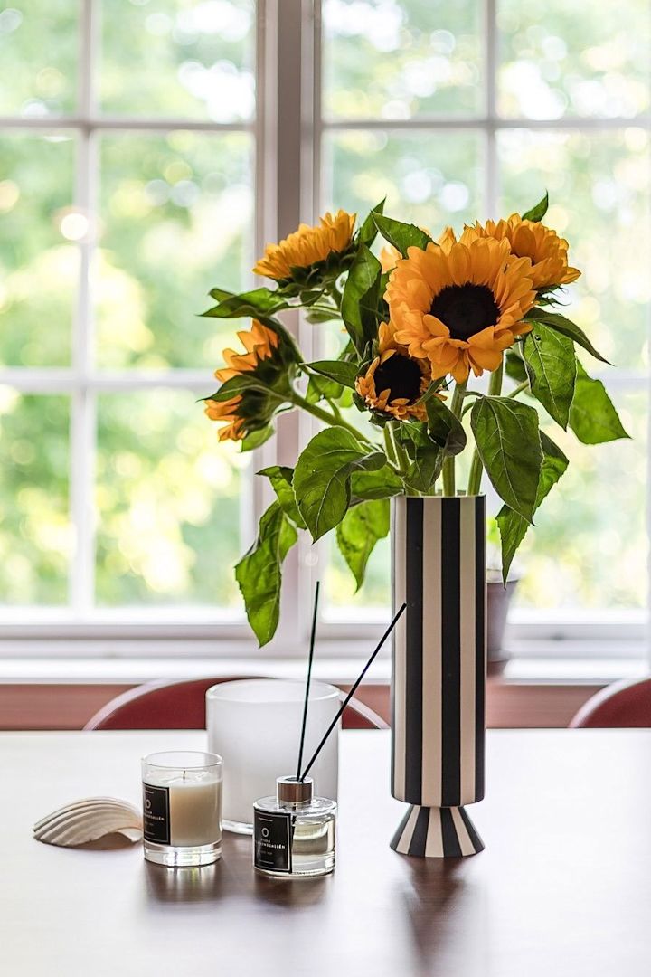 Den bästa vasen för långstjälkade blommor, här ser du en hög vas med svarta och vita ränder fylld med solrosor. 