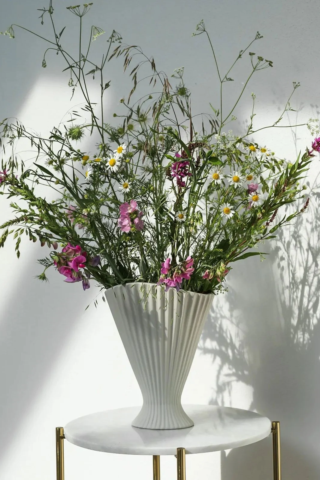 Den bästa vasen för långstjälkade blommor, här ser du en hög vas med svarta och vita ränder fylld med solrosor. 