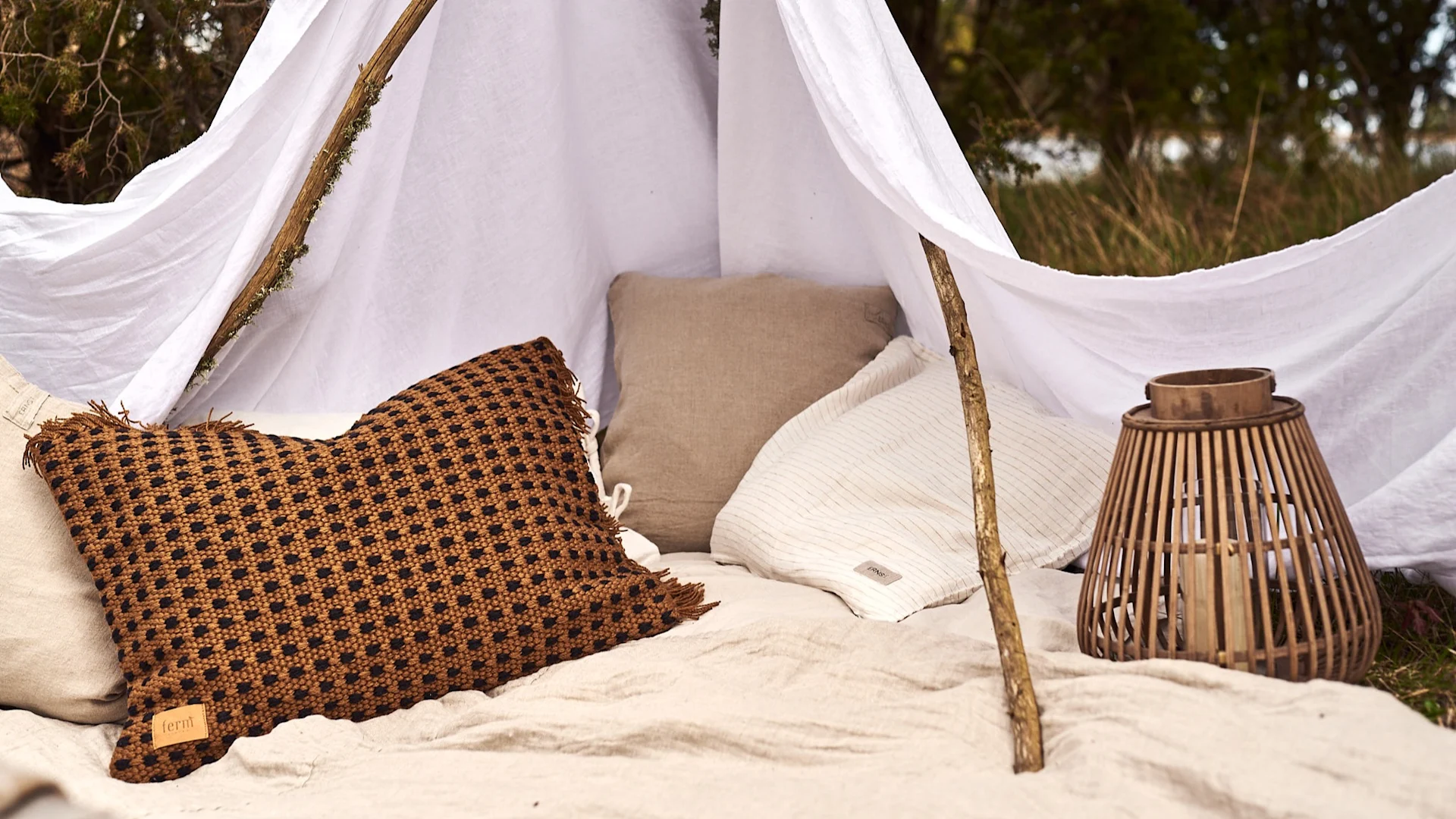 Glamping i skogen på enkelt vis med många kuddar.