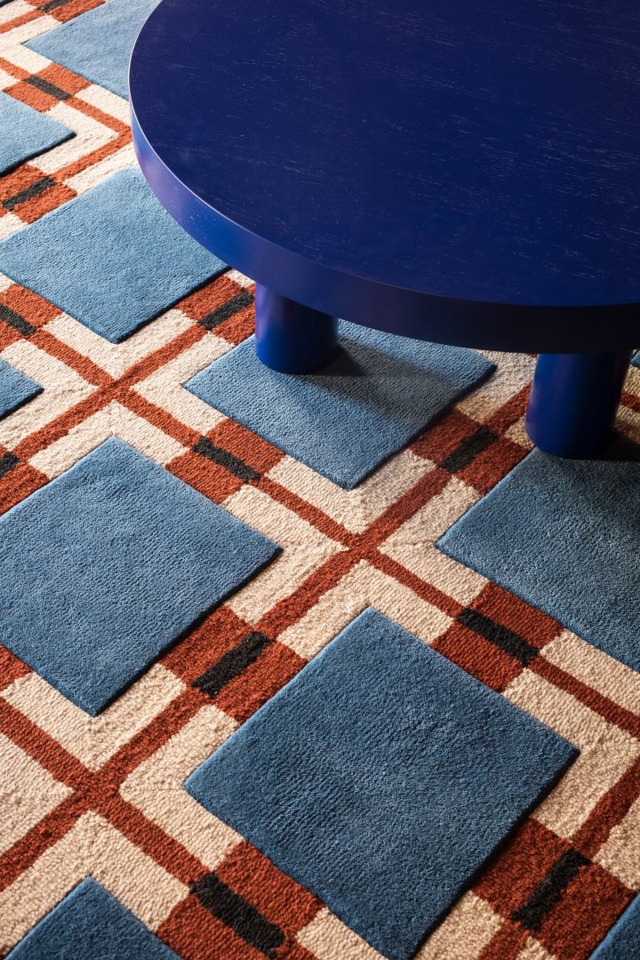 Kombinationen av färg och mönster på textilier och mattor är stort inom inredningstrender 2024, här i röd/blå ullmatta med geometriskt mönster från Layered. 