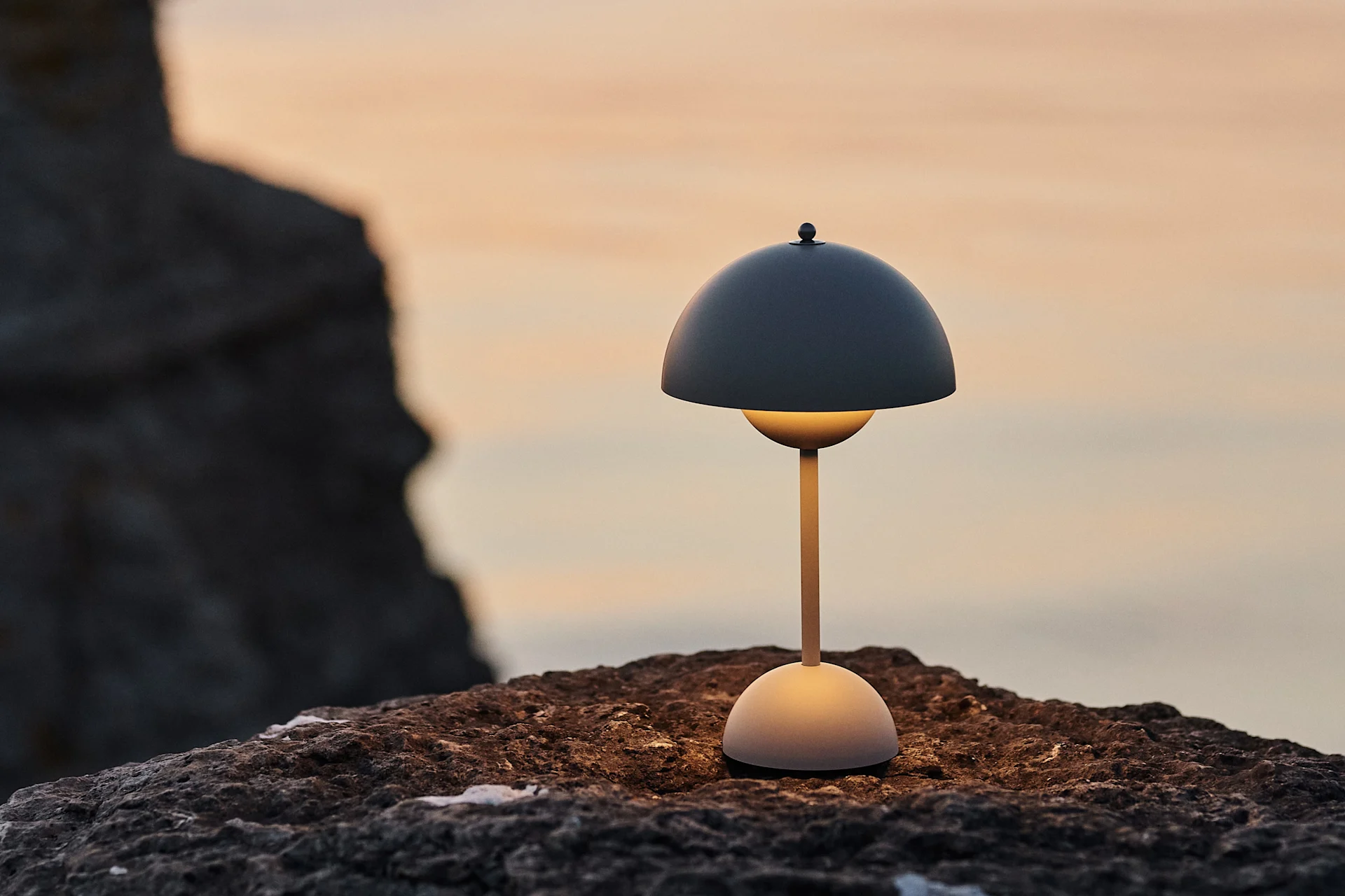 Flowerpot VP9 bärbar bordslampa på raukar i solnedgång