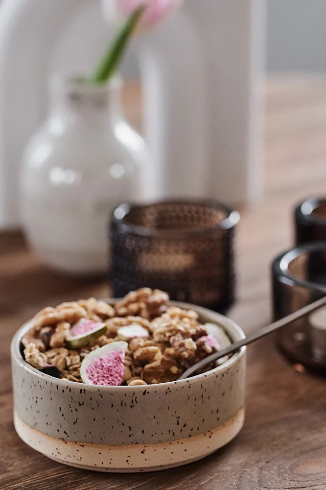 Müsli i en rustik grön skål Lowkey från Paradisverkstaden står på det dukade bordet till frukost. 