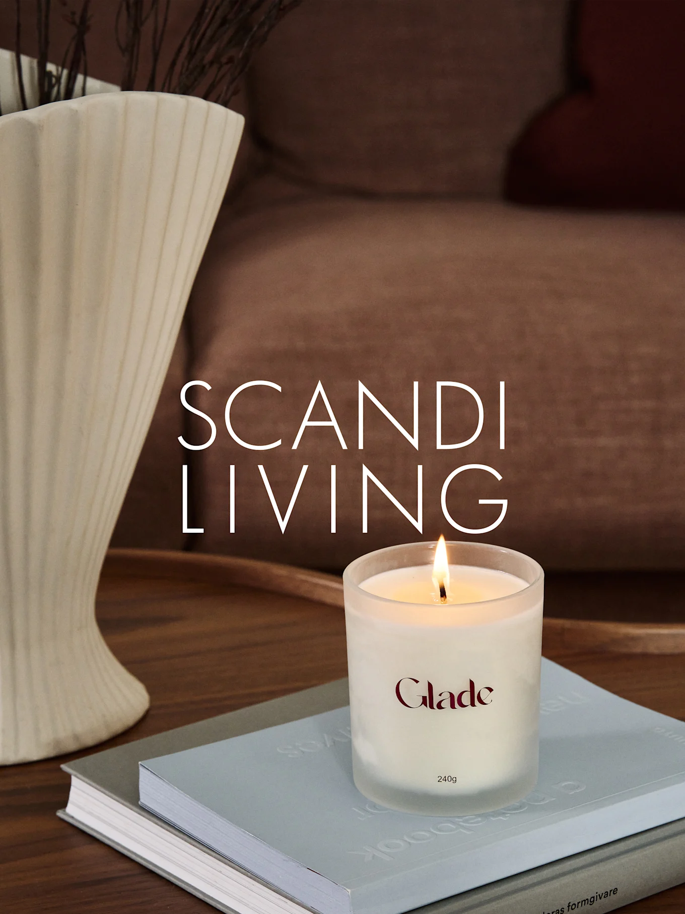 Ett brinnande Glade-ljus på böcker, bredvid en räfflad vas med grenar. Överlagrad text: SCANDI LIVING.