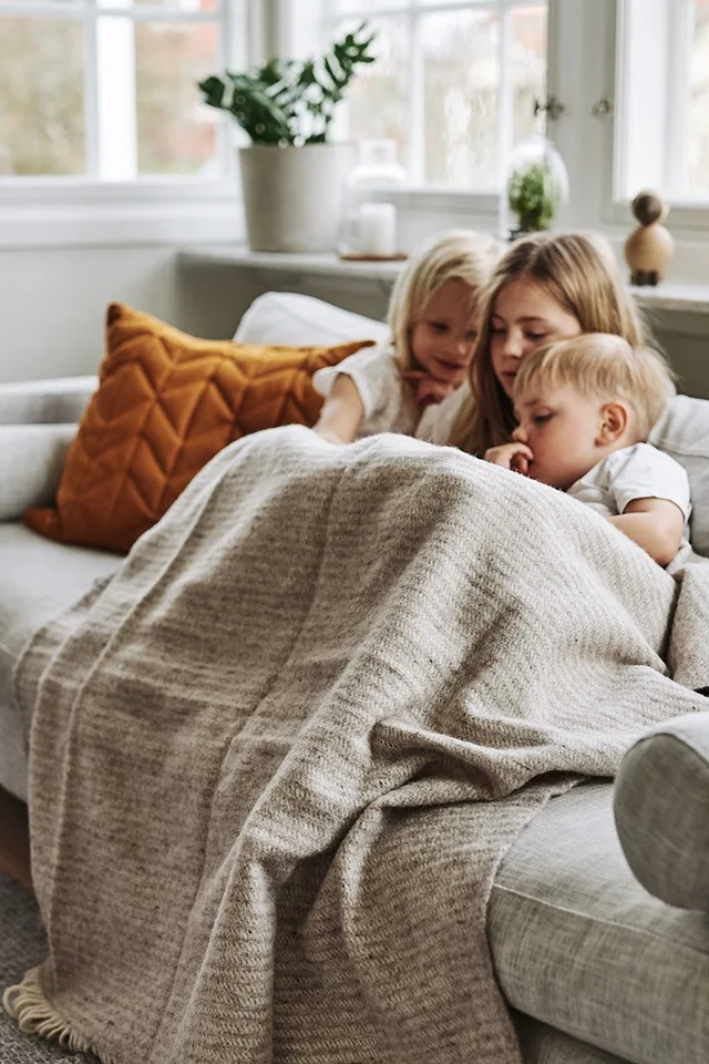 Ralph ullpläd från Klippan Yllefabrik värmer de små som kurat ihop sig i soffan.