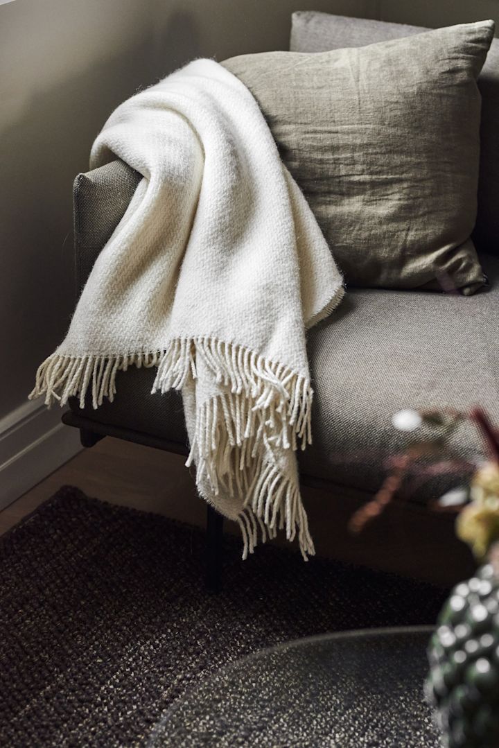 En mysig filt är en utmärkt mors dag-present. Här ser du den vita Sandstone-filten från Scandi Living ligga över en soffa.