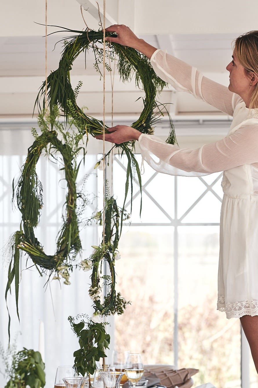 Hänger upp vackra dekorationsringar som välkomnar gästerna till bords för årets midsommarfirande.